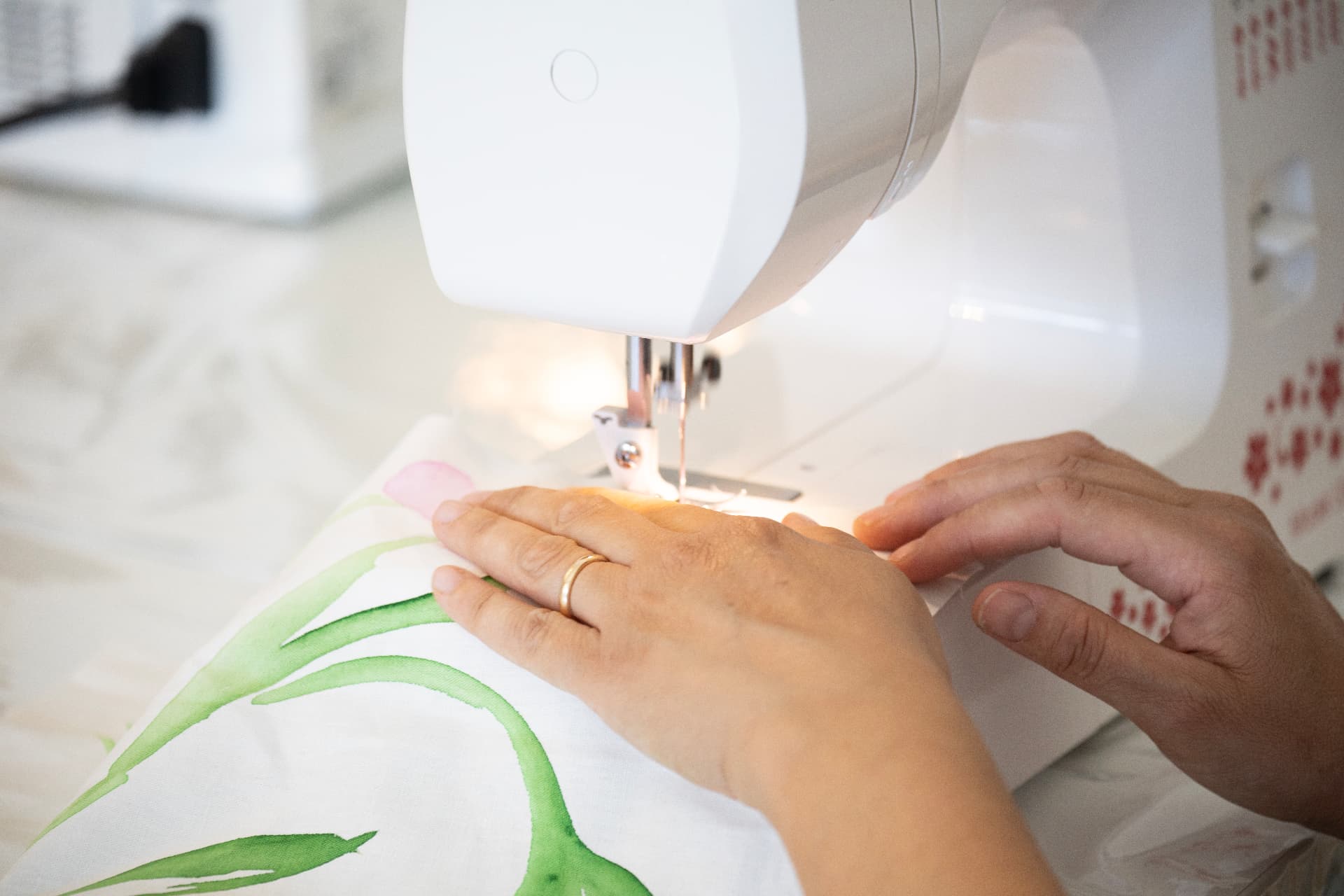 Mani al lavoro alla macchina da cucire su un tessuto dipinto a mano
