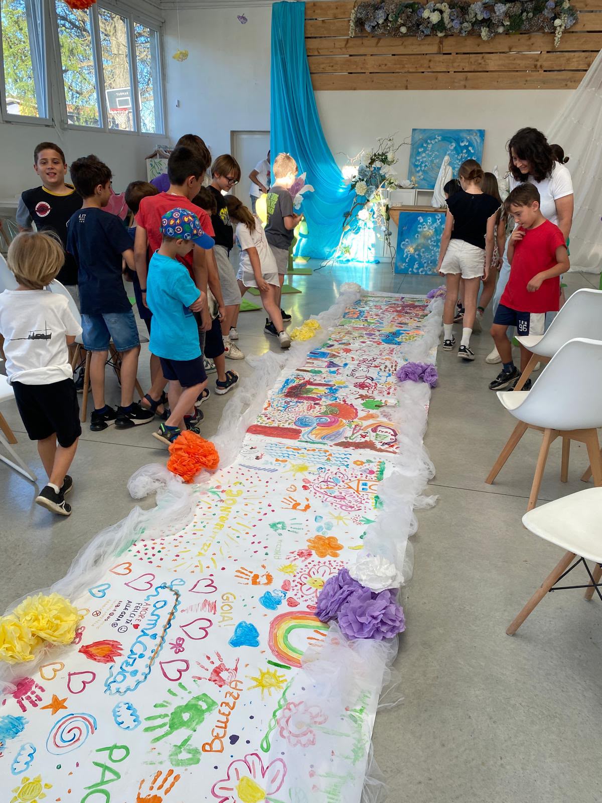 Bambini e ragazzi osservano il lungo cammino dipinto in laboratorio