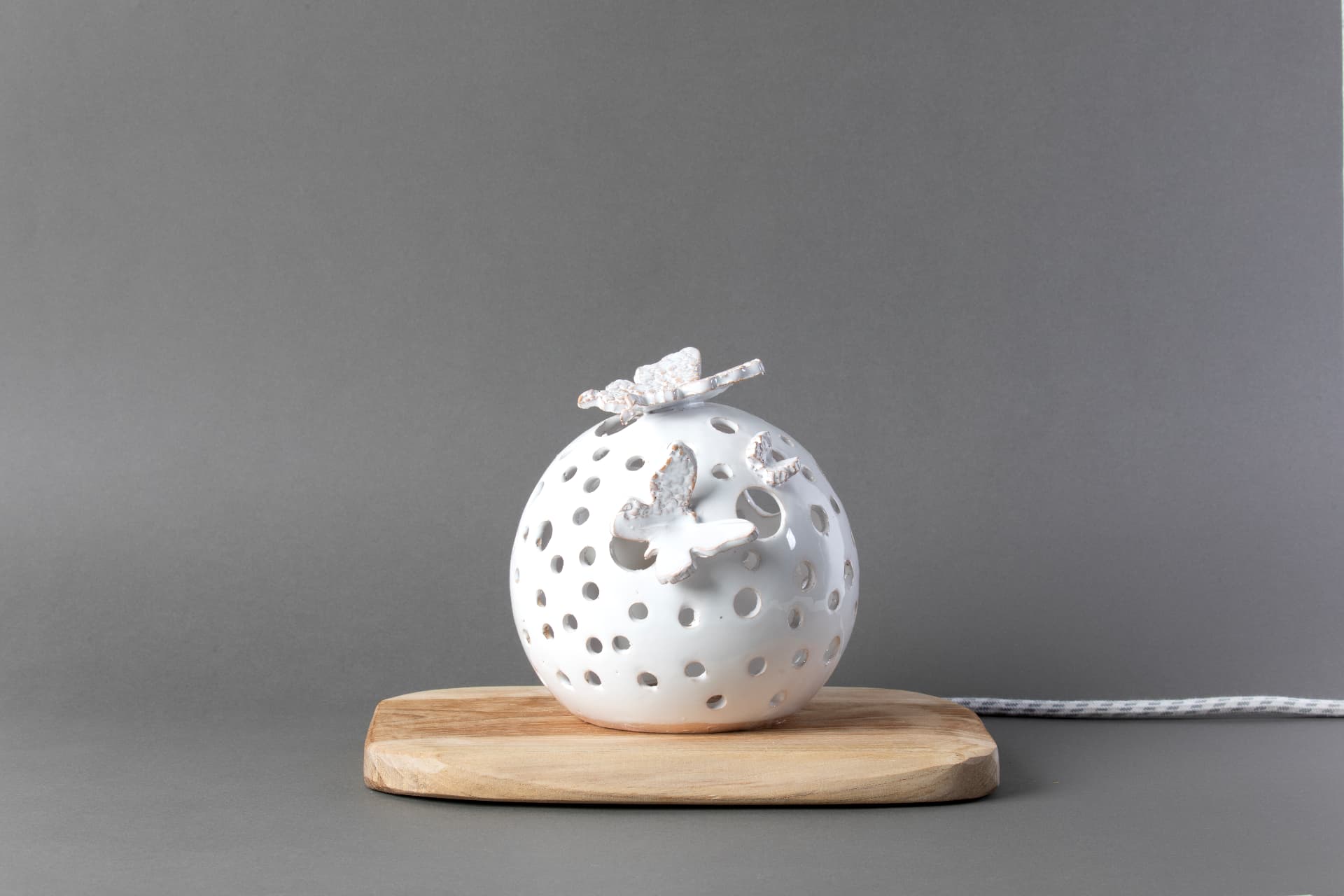 Volo di Luce, lampada sfera traforata in ceramica bianca con farfalle, su base in legno